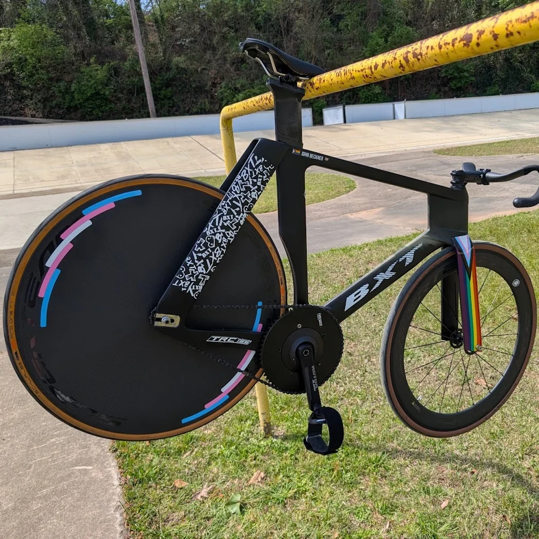 John Beckner's track bike, his name on the top tube, beside an outdoor velodrome