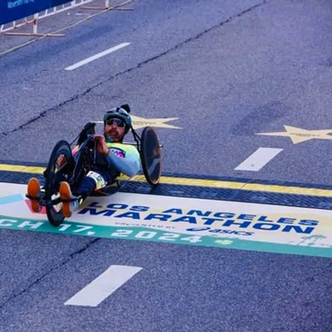 Rob Balucas crossing the 2024 Los Angeles Marathon finish line on his handcycle