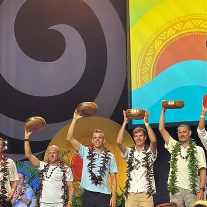 Sam Long and fellow finishers in leis raising wooden bowls on the Kona awards stage